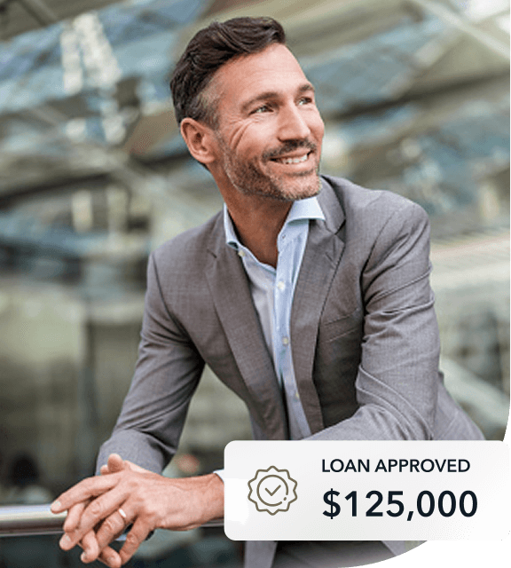 smiling business man leaning on a railing in a building